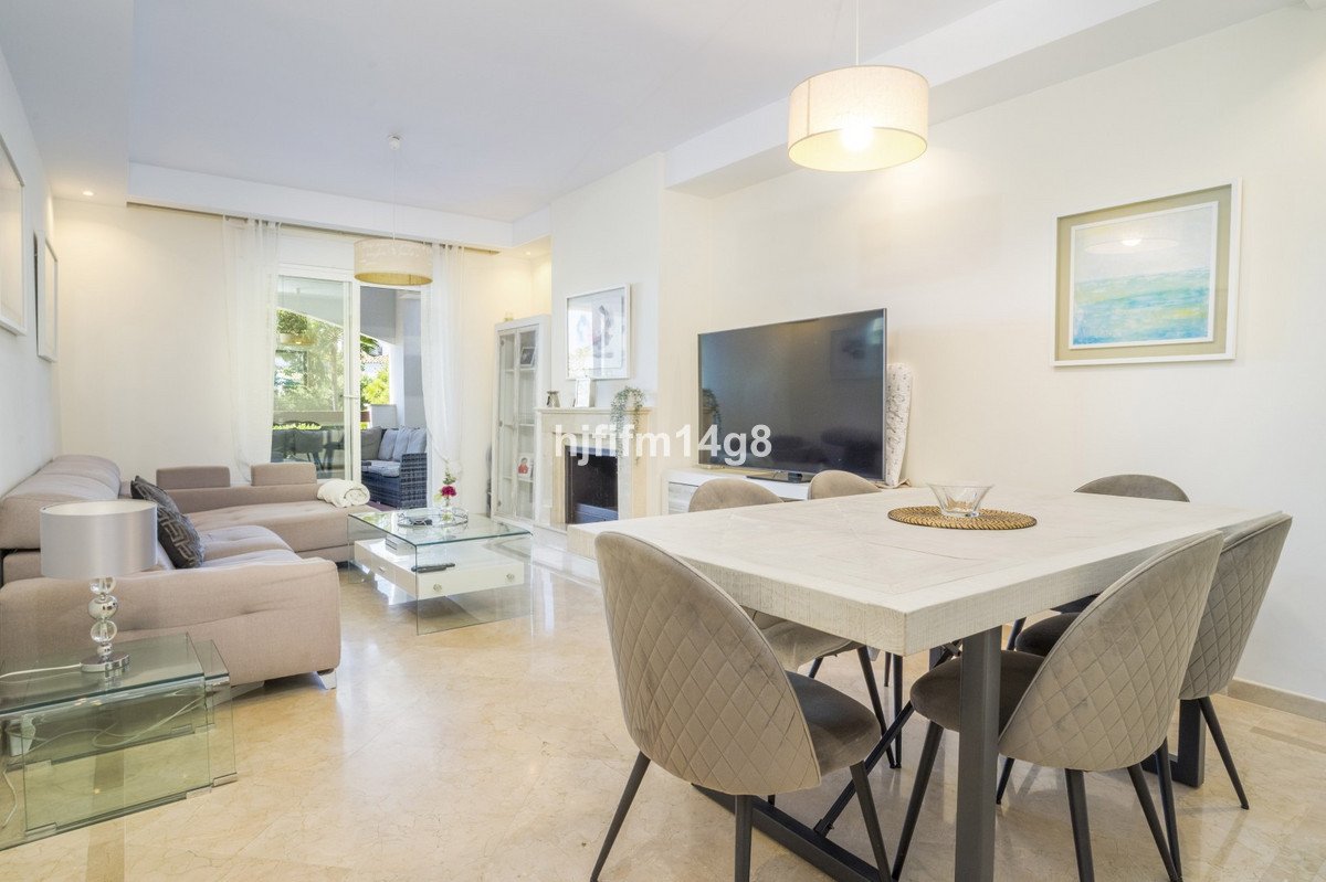 Spacious living and dining room with a large sectional sofa, modern dining table, and a TV, leading to an outdoor patio.