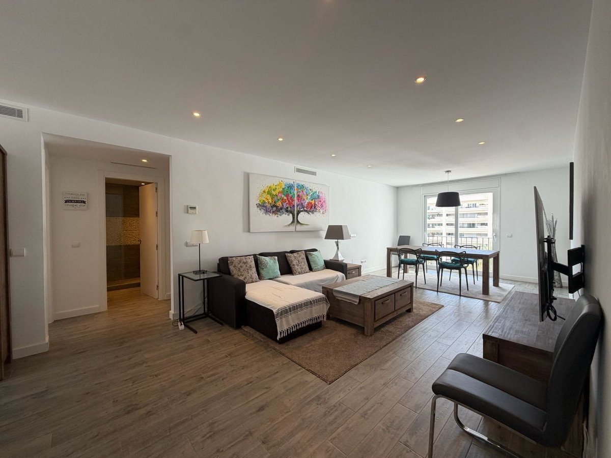 Spacious living and dining area with a modern sectional sofa, dining table, and abstract art on the wall.