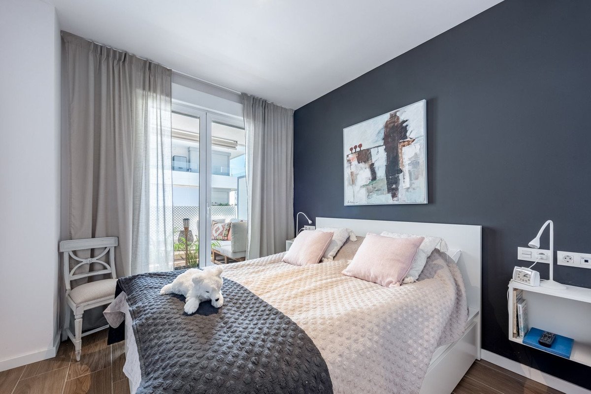 A modern bedroom with a king-size bed, pink pillows, a dark accent wall, and a plush white dog toy.