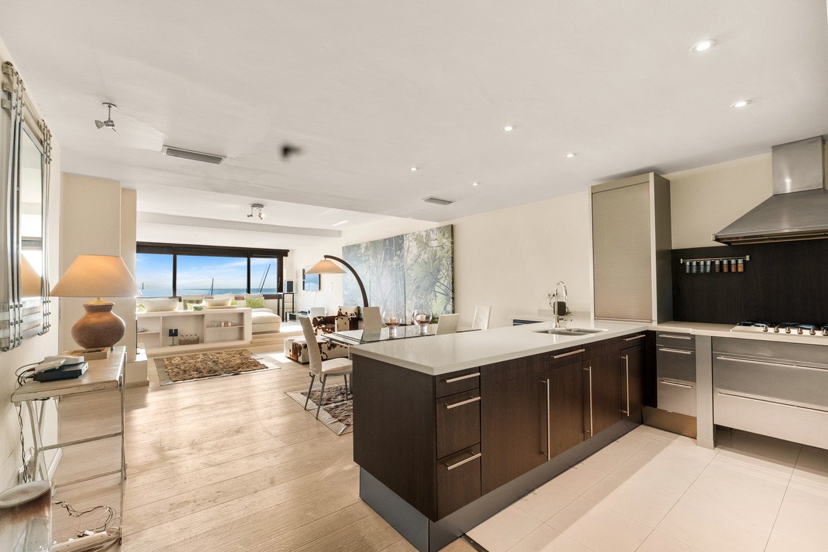 Modern open-plan living dining kitchen with large windows overlooking the sea