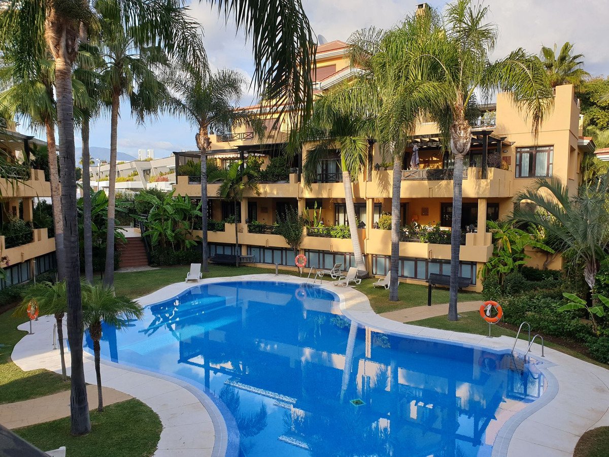 Apartment complex with swimming pool and palm trees in the courtyard