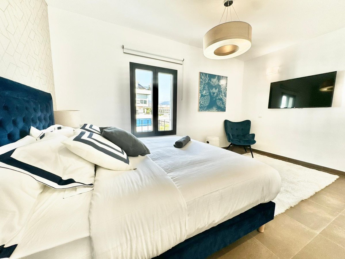 Luxurious bedroom with a large bed, a tv, and a balcony door offering a pool view.