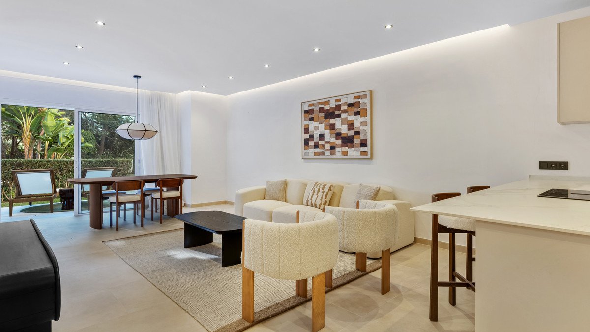 Modern living and dining area with a view of lush greenery and outdoor seating.