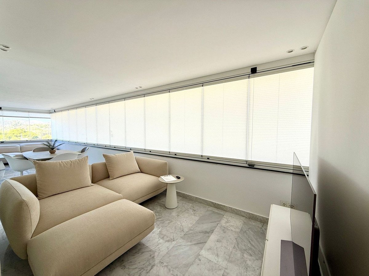 Modern living area with a large sectional sofa, dining table, and panoramic windows offering a scenic view.