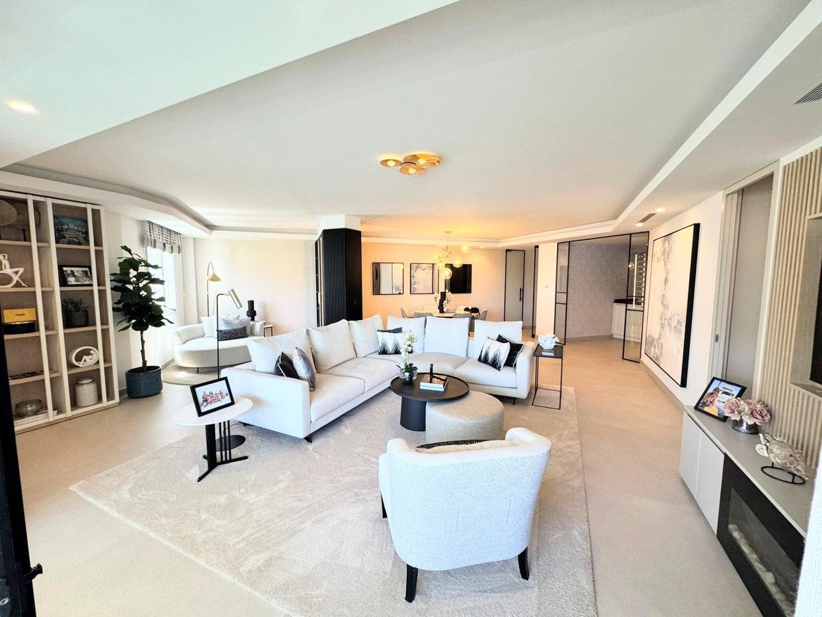 Spacious modern living room with white sofas, a large rug, built-in bookshelves, and abstract art on the walls.