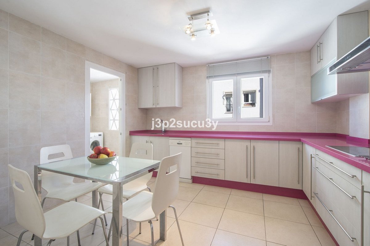 Modern kitchen with white and pink cabinets, glass dining table, and fruit bowl