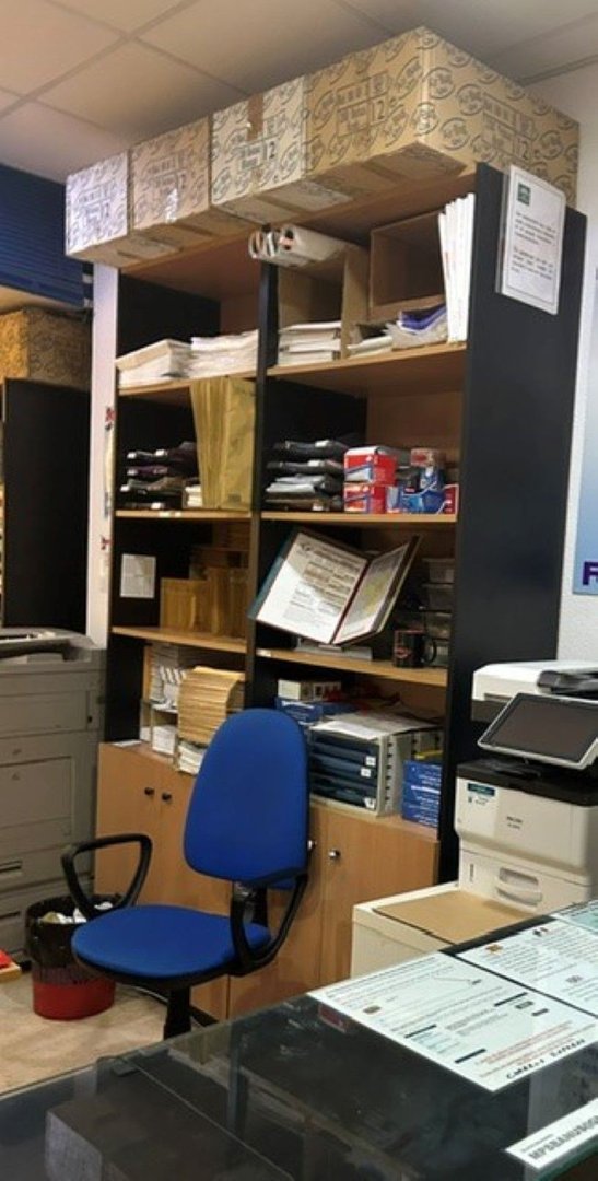 Office space with shelves full of documents, a blue office chair, and a printer on the counter.