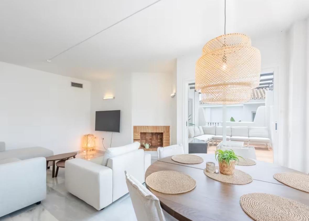 Modern living and dining area with a fireplace, a large pendant light, and patio access with outdoor seating.