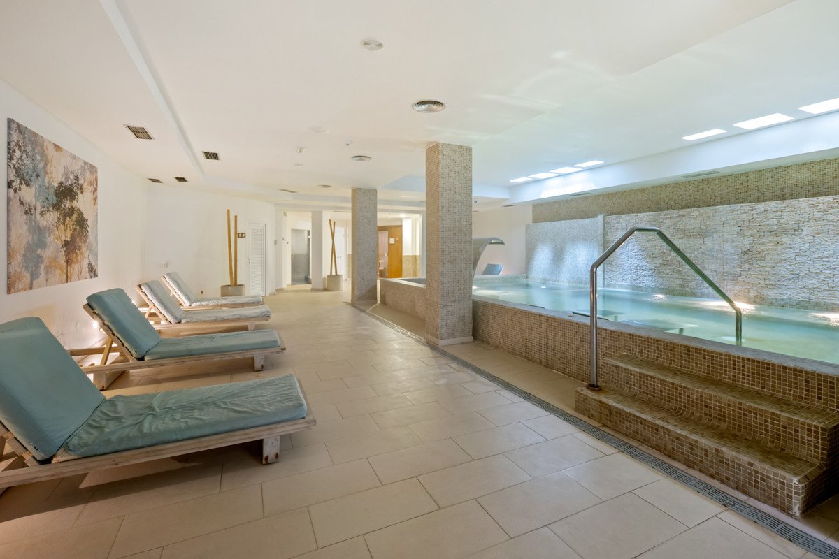 Indoor swimming pool with tiled steps and lounge chairs along the side
