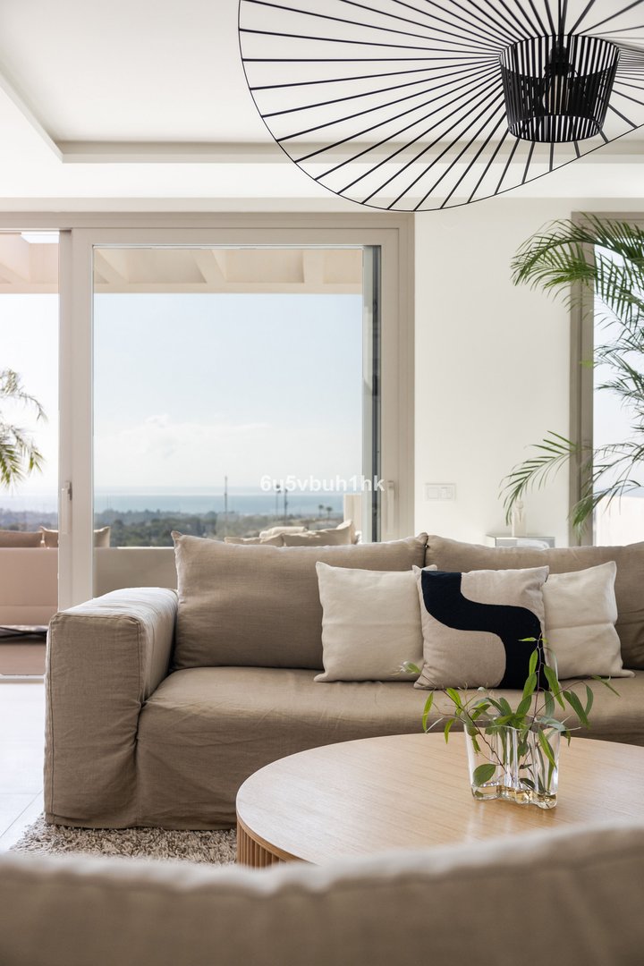 Modern living room with a large sofa and ocean view through sliding glass doors.