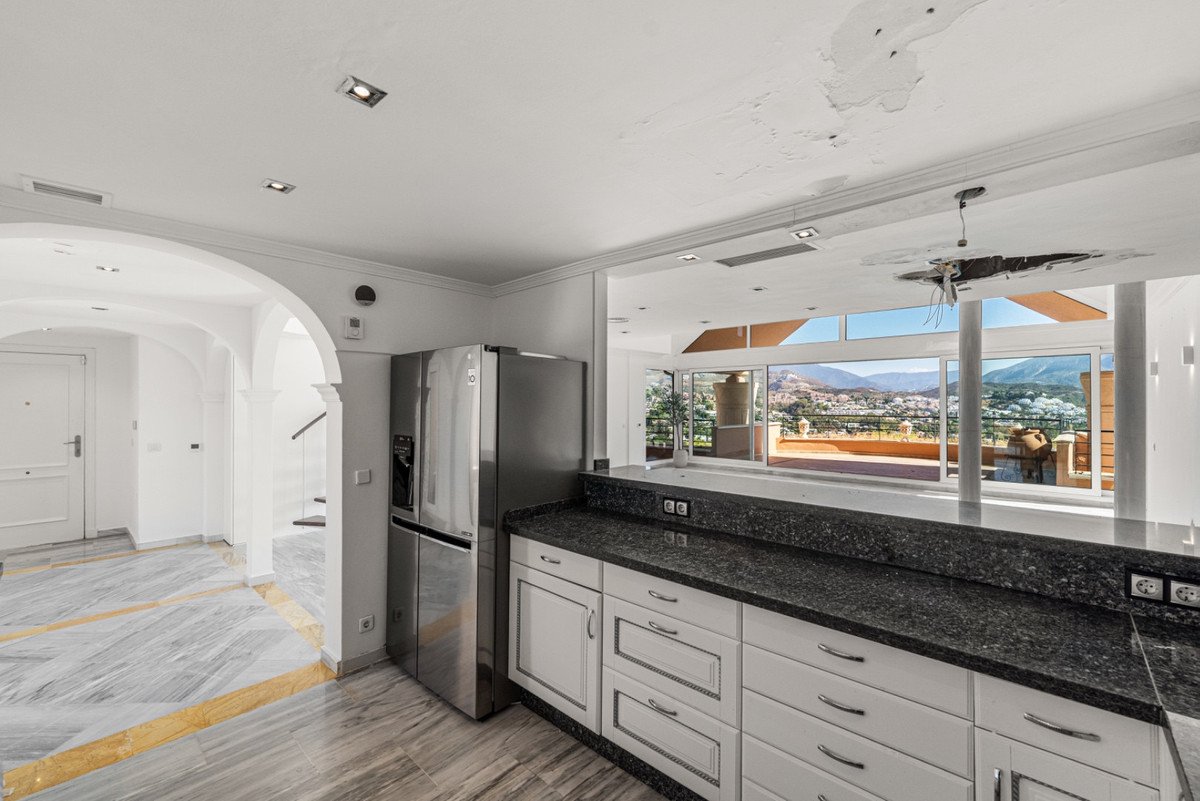 Modern kitchen with granite countertops and a large window offering a stunning panoramic mountain view and balcony access.