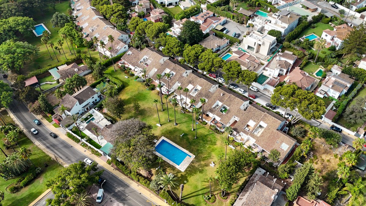 Aerial view of a residential area with villas, pools, and lush greenery.