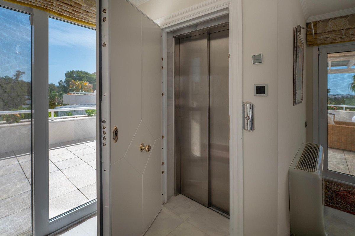 Modern hallway with elevator, glass doors to balcony, and ocean view.