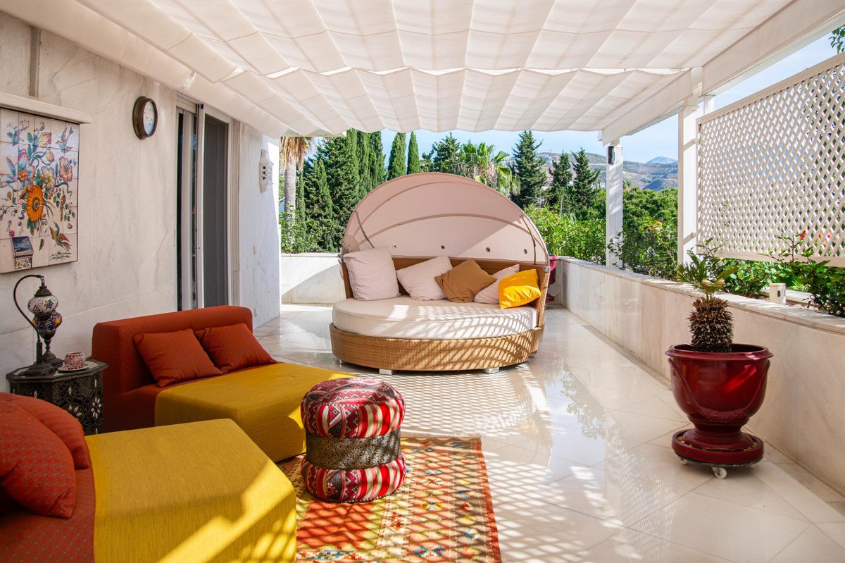 Covered patio with round daybed, colorful furniture, and mountain views.