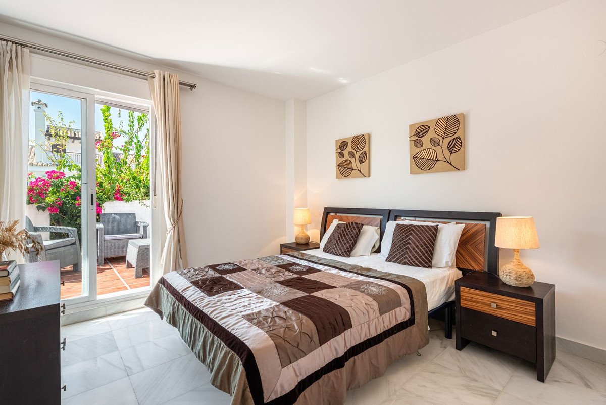 Bedroom with a king-size bed, access to a terrace with outdoor seating and vibrant flowers.