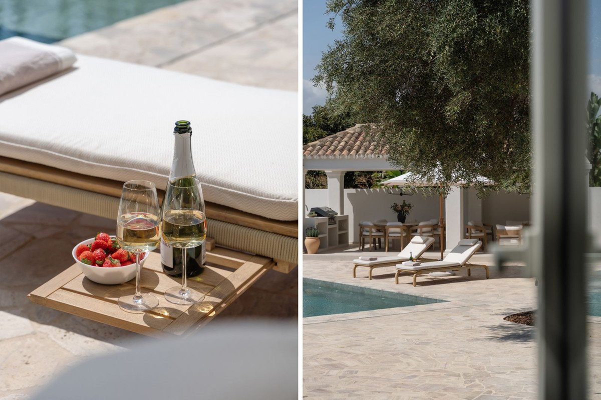 Two sun loungers by a swimming pool, with an outdoor dining area and bottle of champagne and strawberries on a tray.