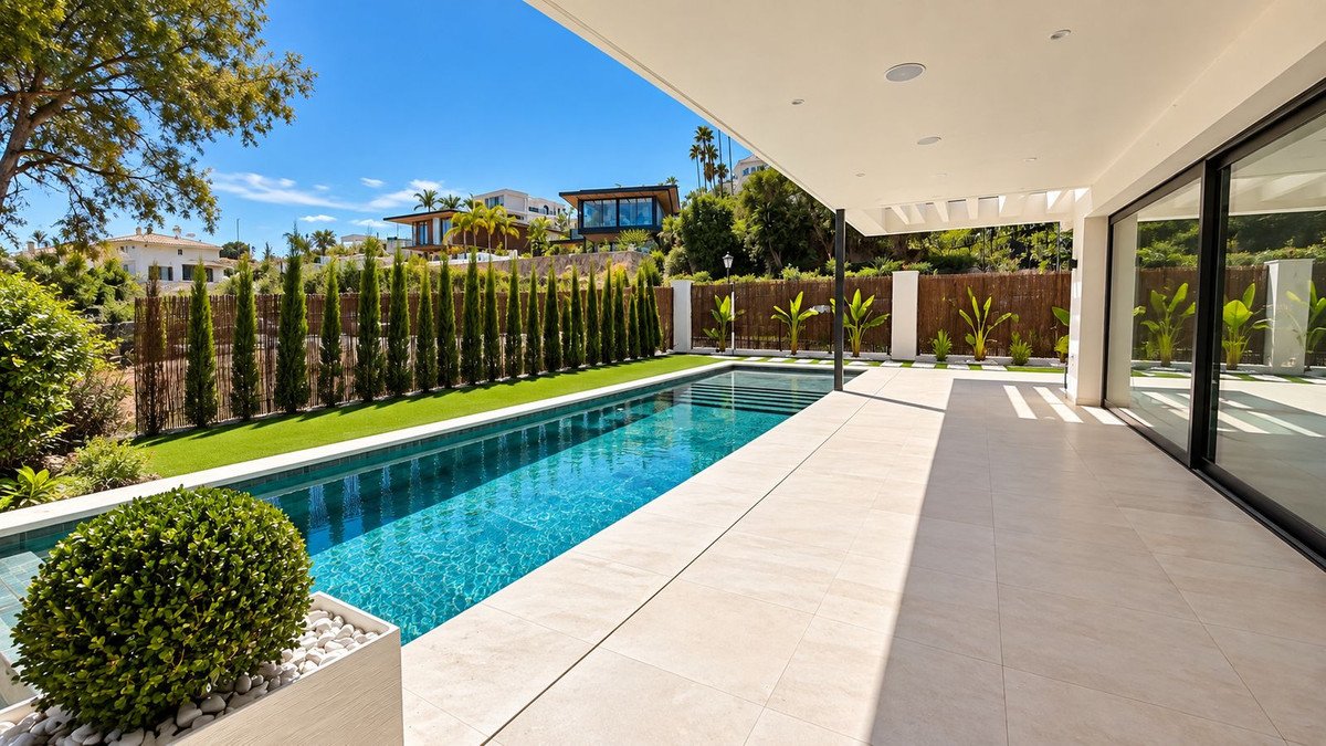 Modern villa with infinity pool and terrace, offering stunning views of lush greenery and surrounding luxury homes.