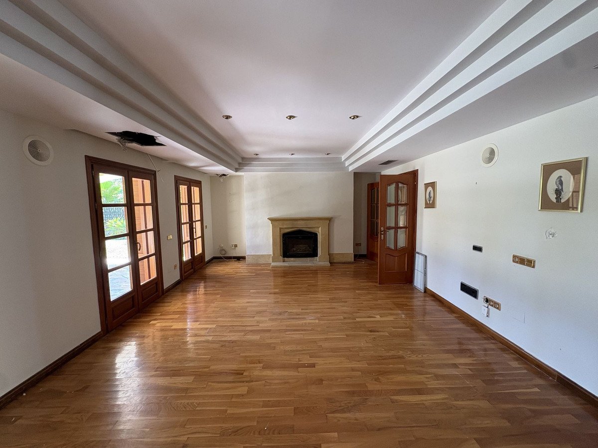 Spacious living room with wooden floors, a fireplace, and large glass doors leading outdoors.
