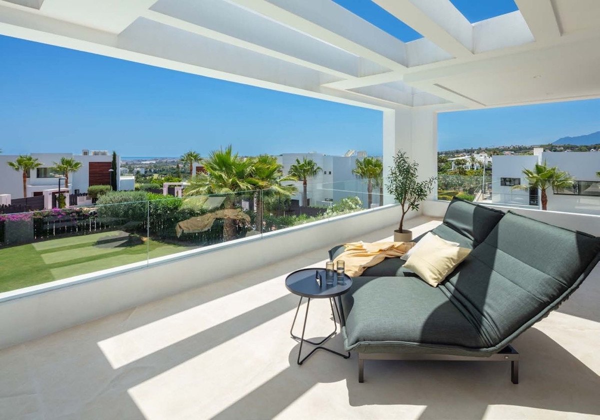 Modern terrace with lounge bed, small table, and panoramic sea and mountain views in a residential complex.