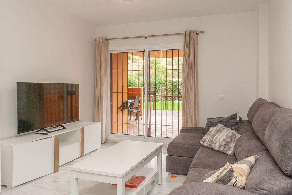 Living room with gray sofa, white coffee table, TV, and sliding doors to outdoor patio.