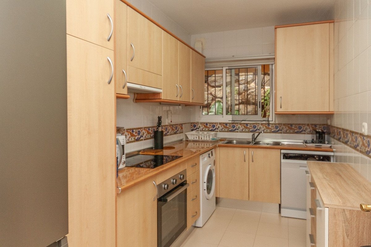 A kitchen with light wood cabinets, tiled backsplash, and appliances.