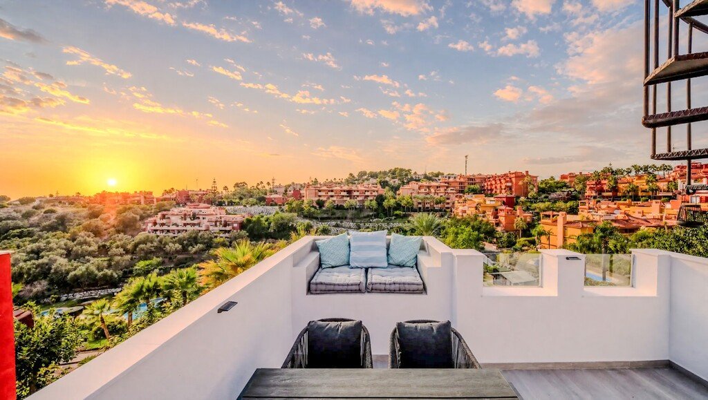 Rooftop terrace with seating and sunset view over town