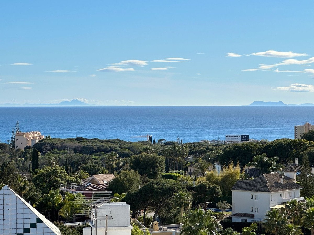 Panoramic view of the sea with distant mountains and lush green vegetation surrounding villas.