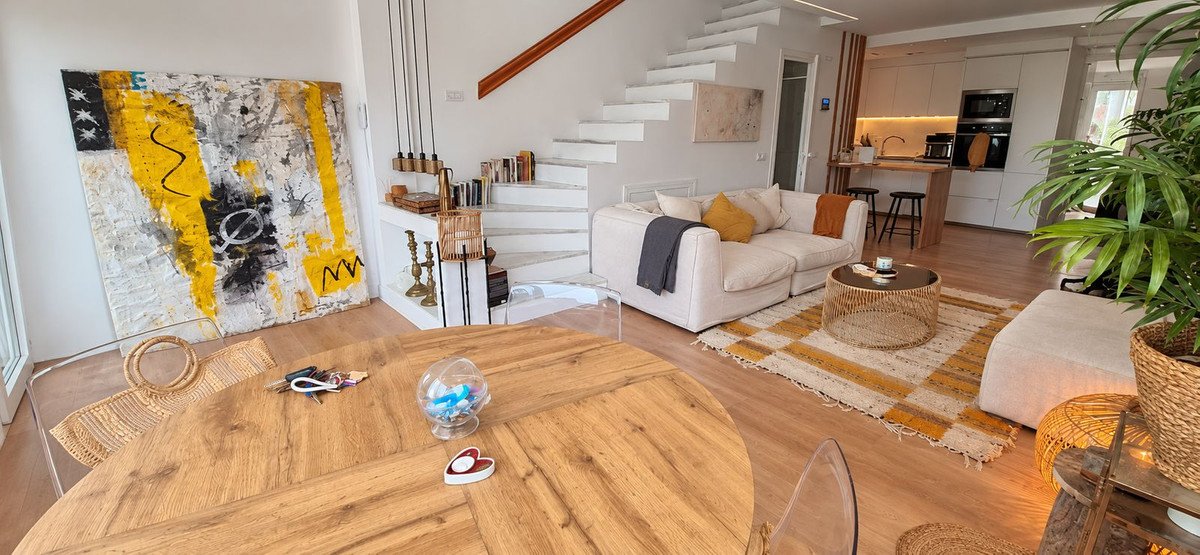 Modern living room with abstract art, a sofa, coffee table, and a view of the open-plan kitchen.