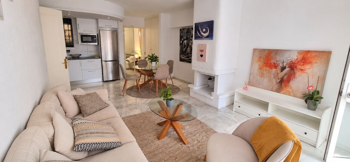 Modern living room with open kitchen, dining area, fireplace, and contemporary art on the walls.