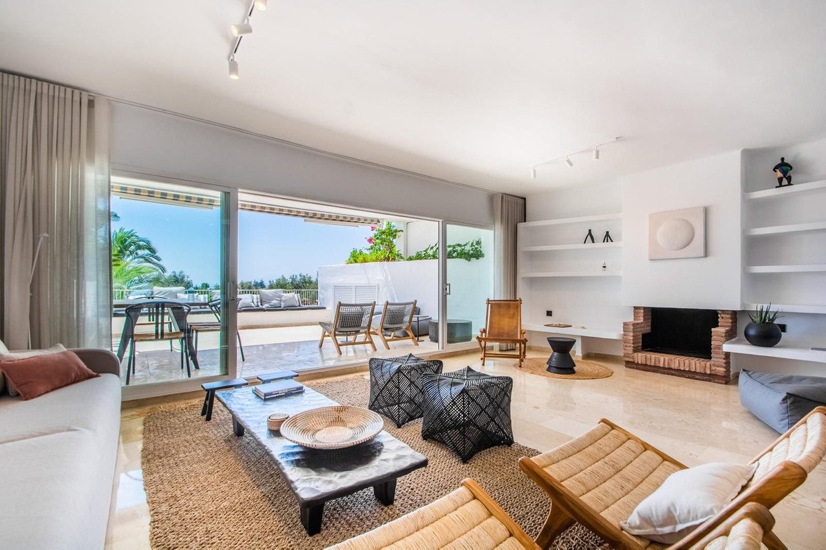 Modern living room with a large terrace offering a sea view and outdoor seating area.