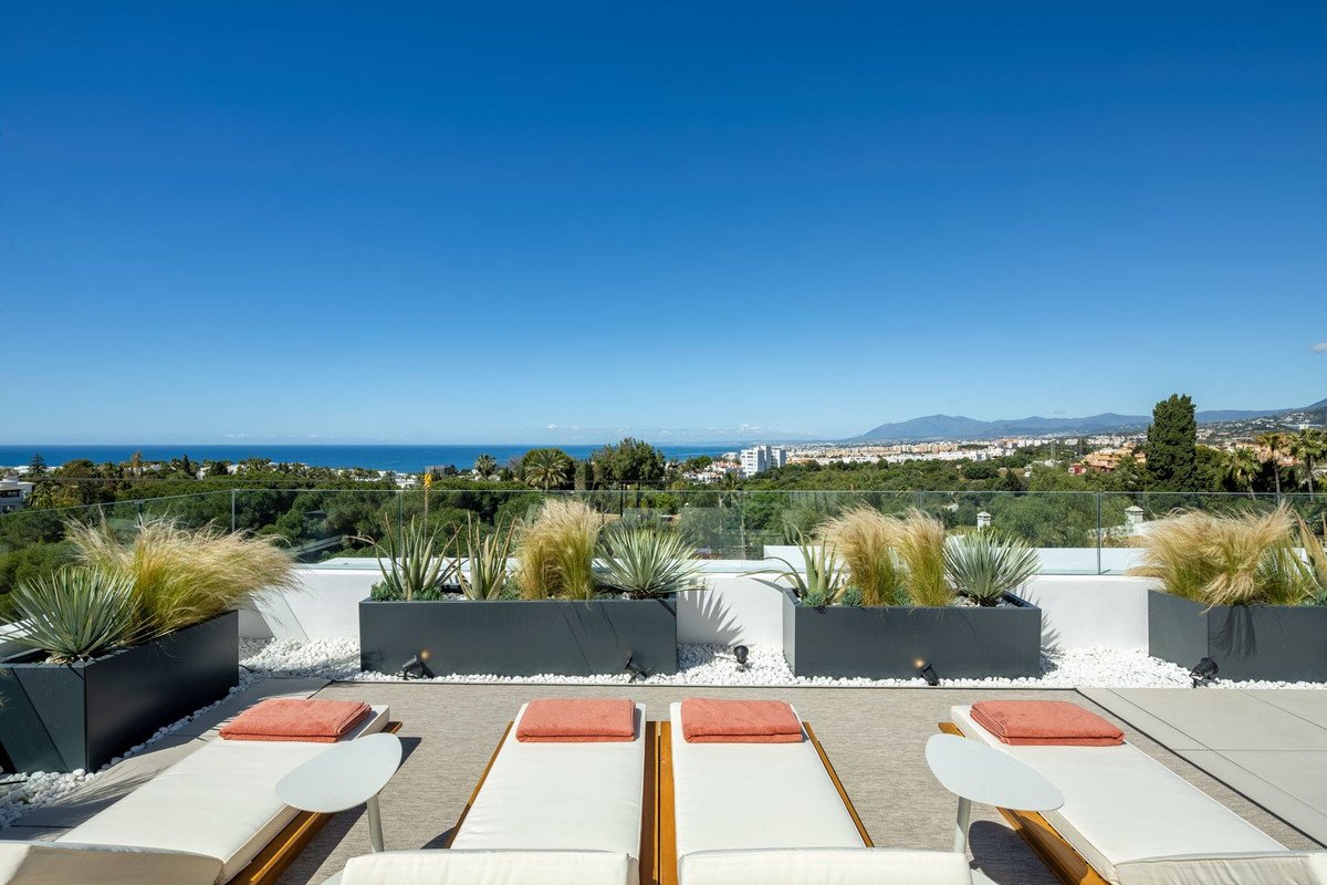 Rooftop terrace with lounge chairs overlooking sea and cityscape