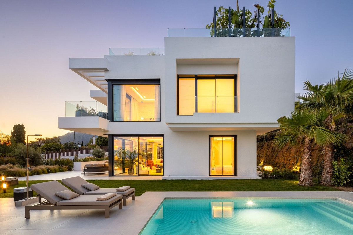 Modern villa with swimming pool, outdoor lounge chairs, and palm trees in the garden