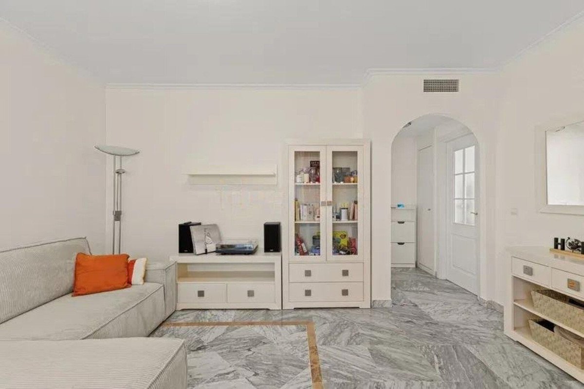 Modern living room with a comfortable sofa, display cabinet, and marble flooring. Features include a floor lamp and a TV stand.