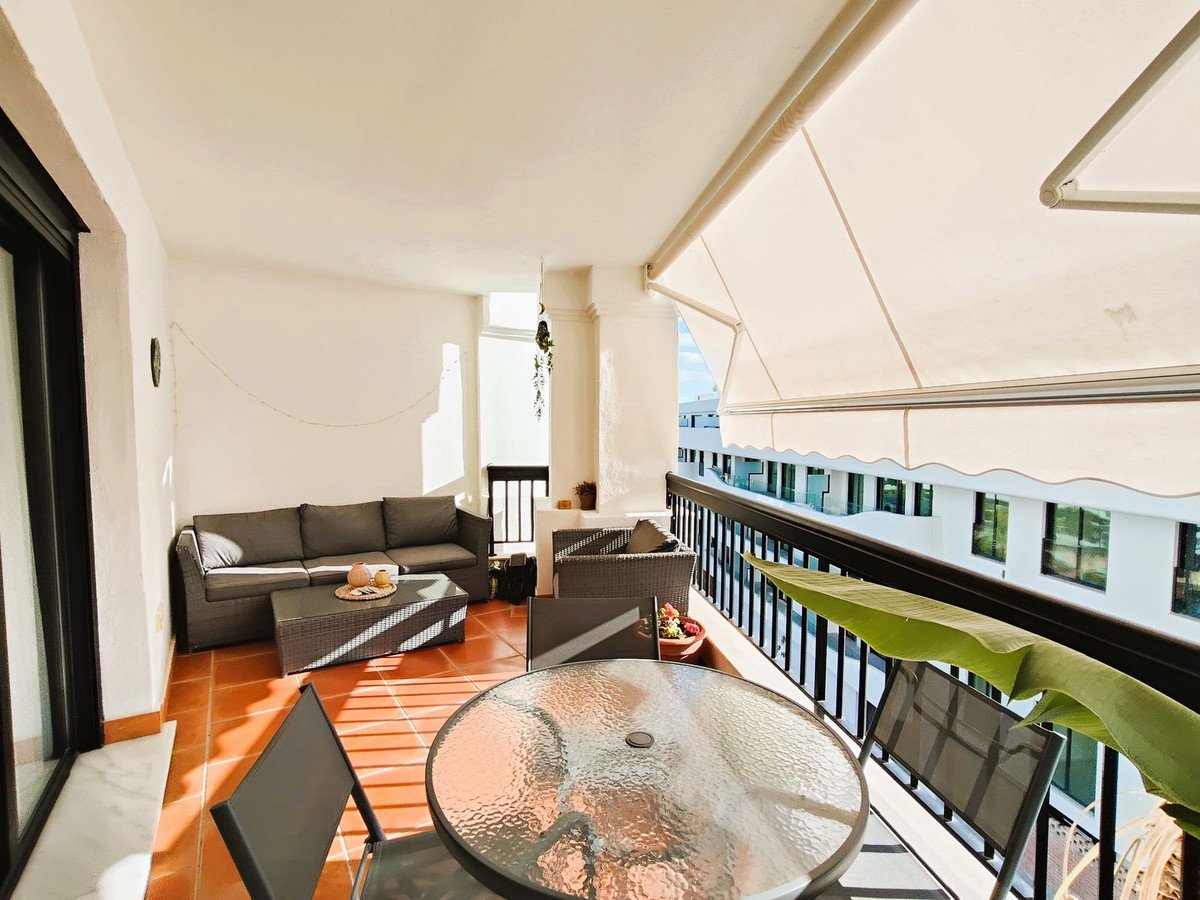 Balcony lounge with shaded terrace, outdoor seating, and city view.