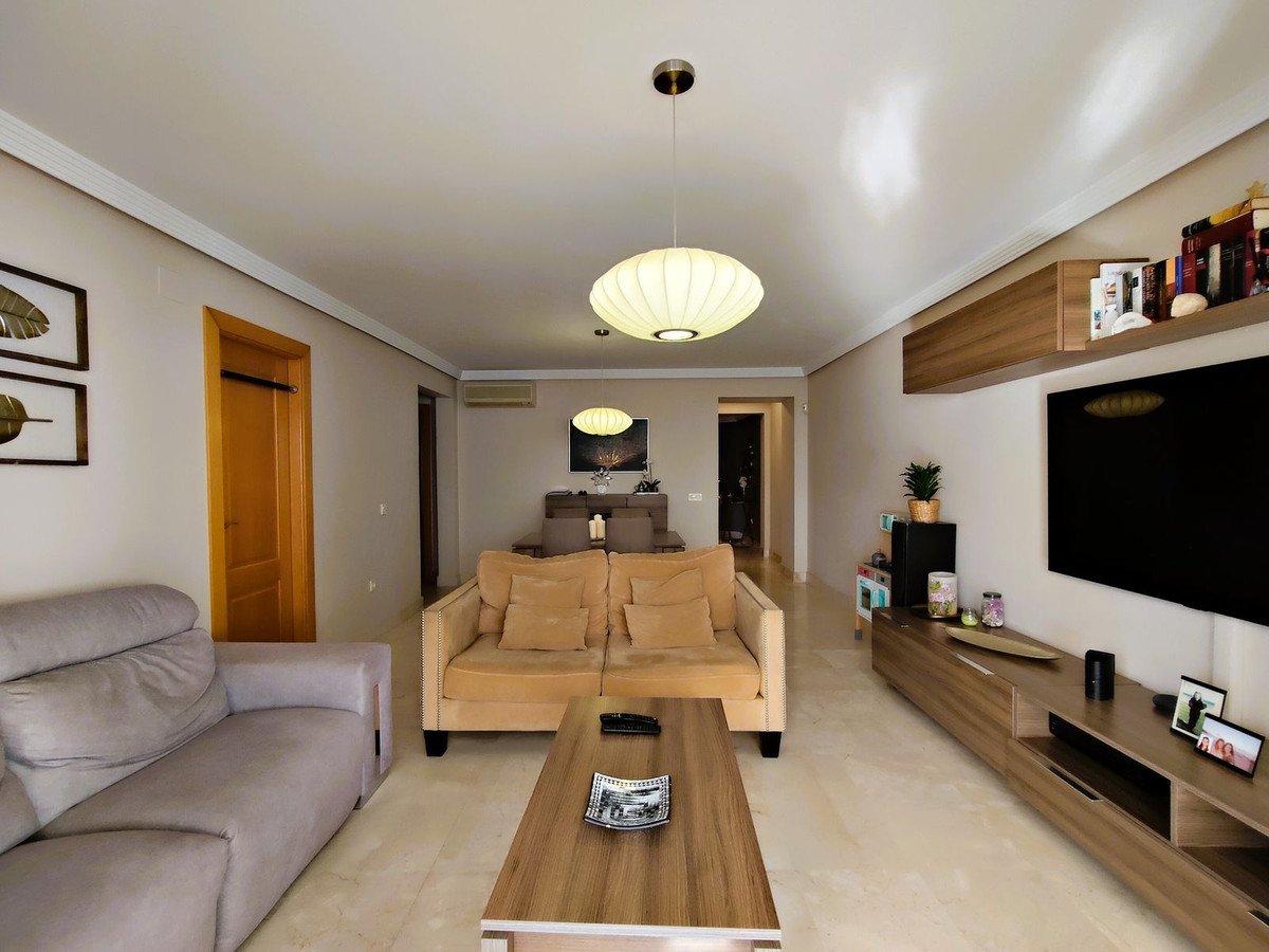 Modern living room with beige sofa, wooden coffee table, and wall-mounted TV.