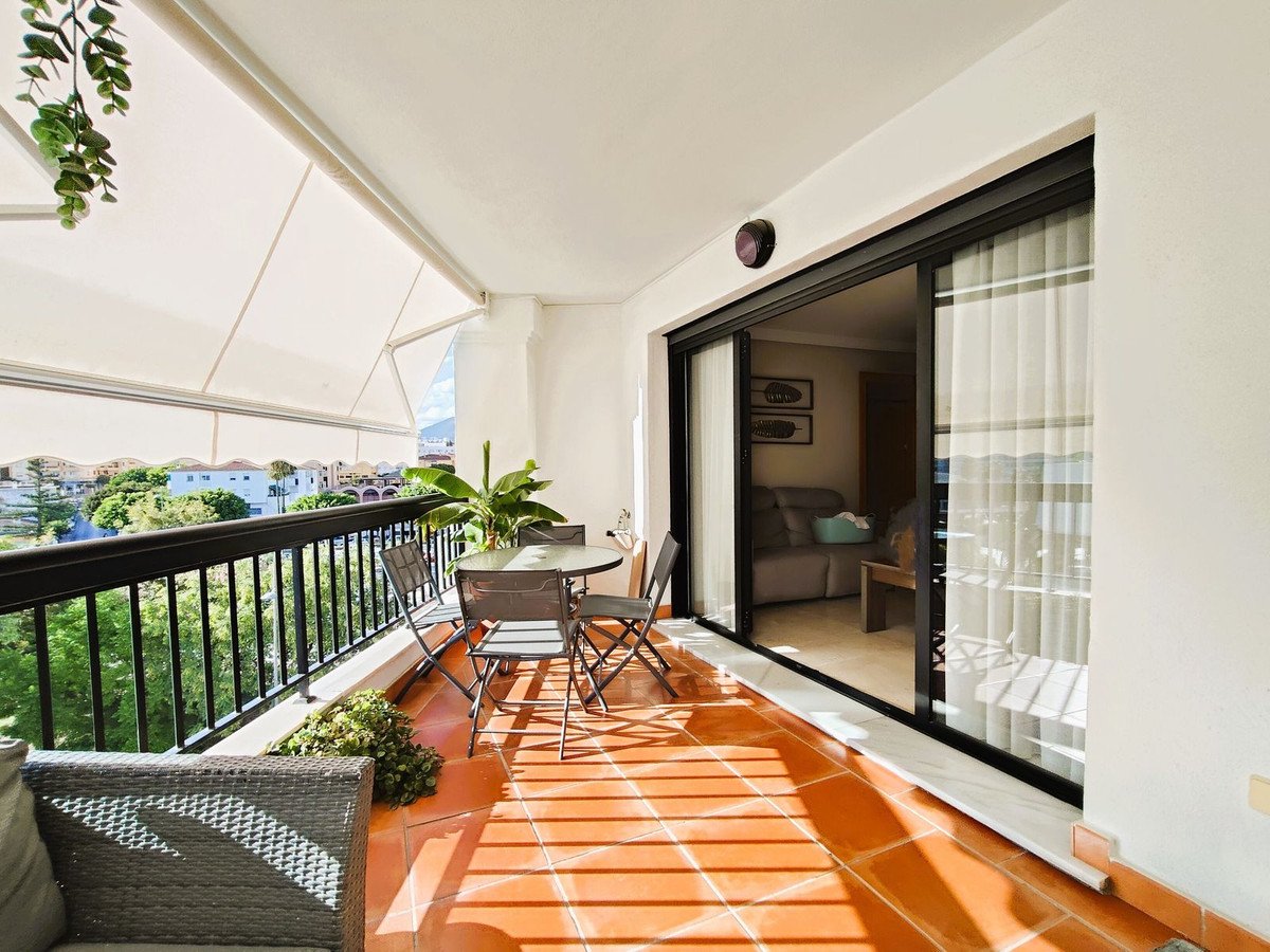 Balcony with outdoor dining set, sliding glass door to living room, and scenic view.
