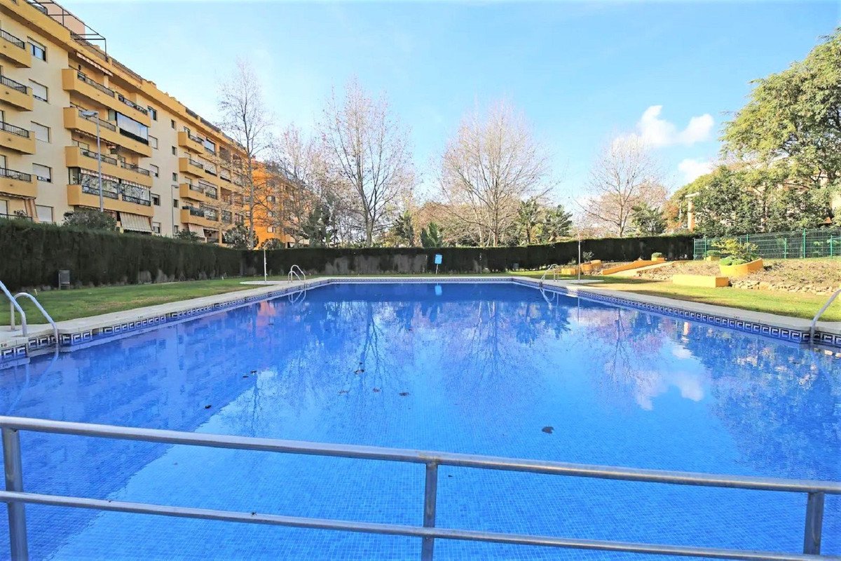 Outdoor swimming pool in an apartment complex with clear blue water and surrounding buildings