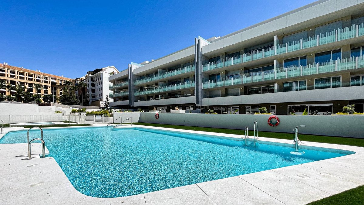 Modern apartment complex with a large outdoor swimming pool and clear blue water