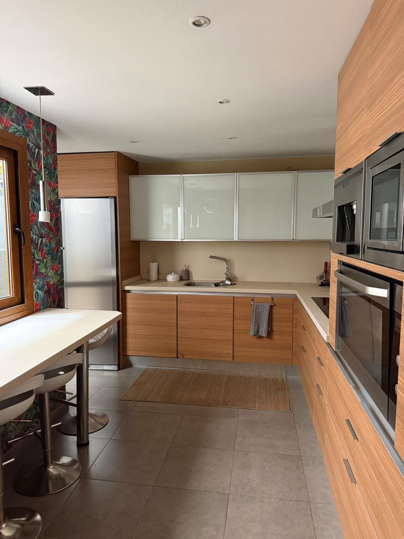 Modern kitchen with wooden cabinets, stainless steel appliances, and a dining area