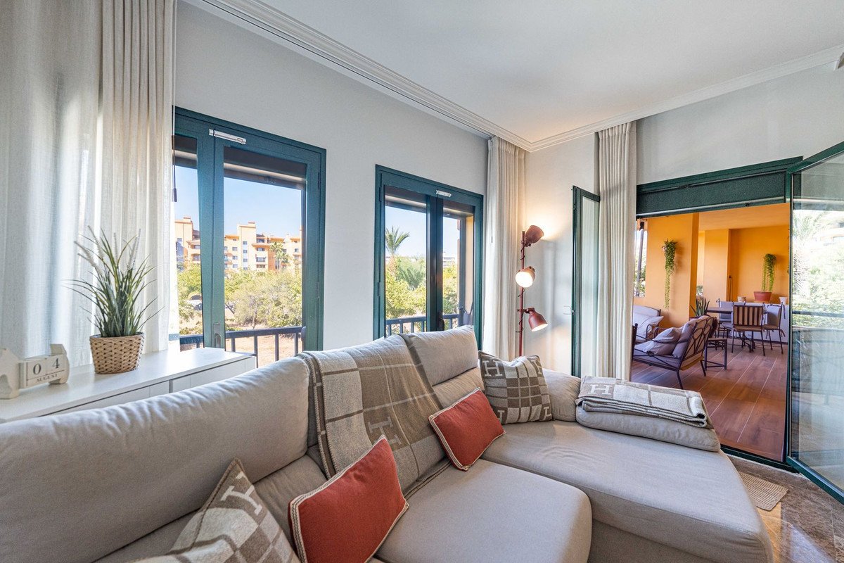 Comfortable living room with a sofa, balcony view, and access to an outdoor terrace with seating.