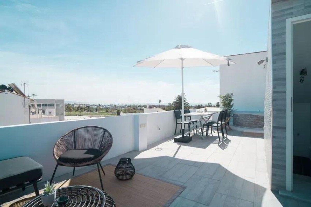 A modern terrace with outdoor dining furniture and a large umbrella, offering a scenic view of the surrounding landscape.