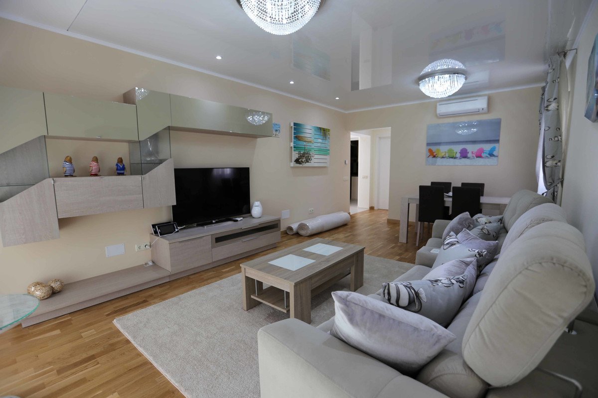Modern living room with a large TV, comfortable sofa with decorative pillows, and a sleek entertainment center.