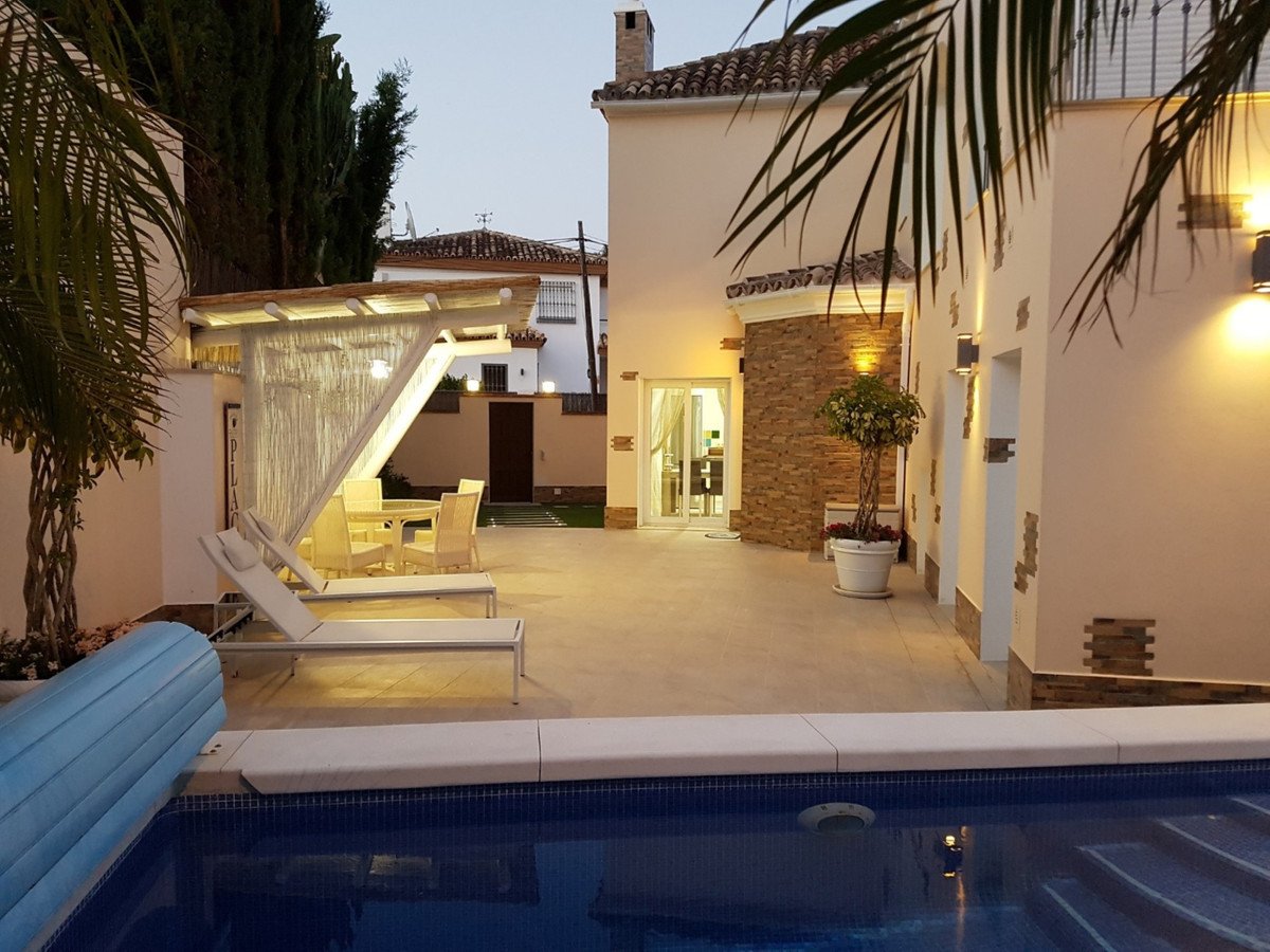 Villa patio with pool, lounge chairs, and outdoor dining area at dusk