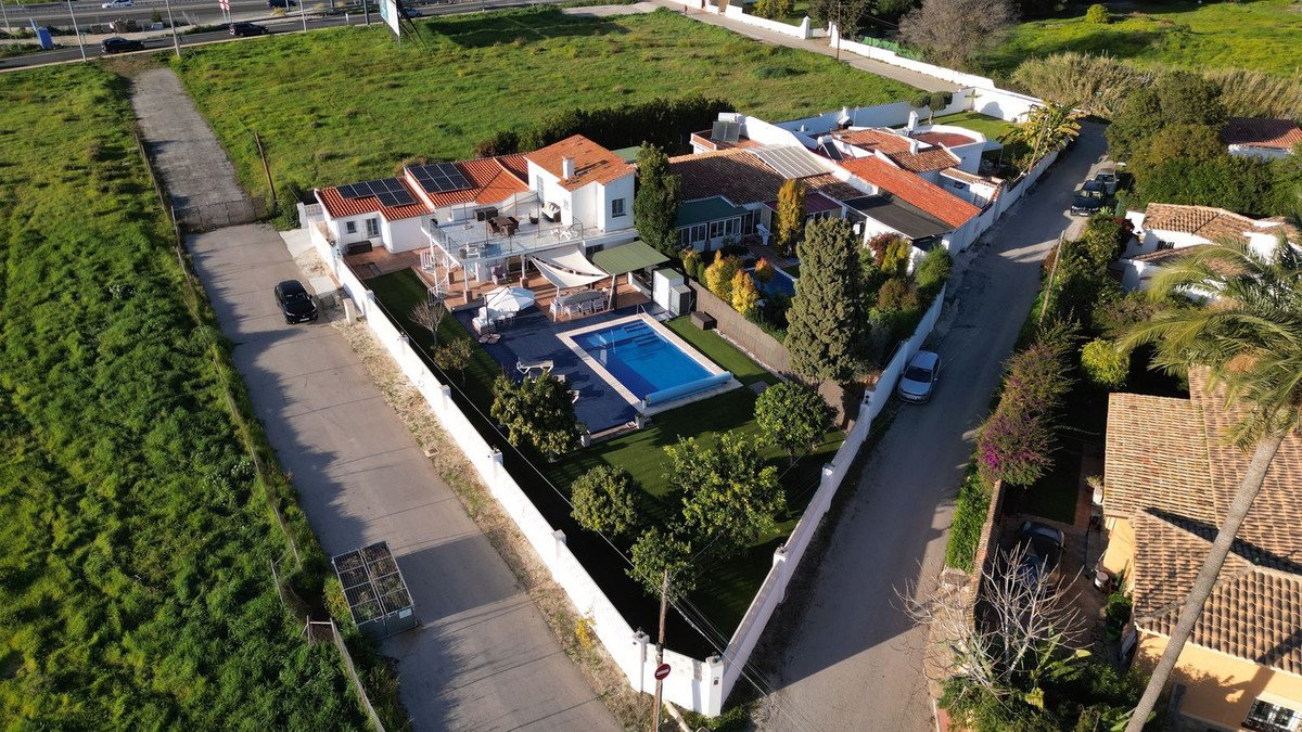 Aerial view of a villa with a swimming pool, large terrace, and garden, featuring solar panels on the roof.
