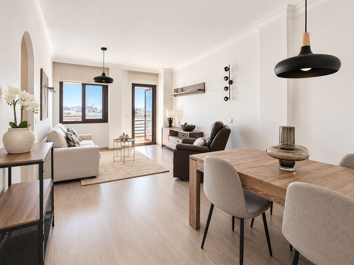 Modern living and dining area with a sofa, table, chairs, and balcony access with city views.