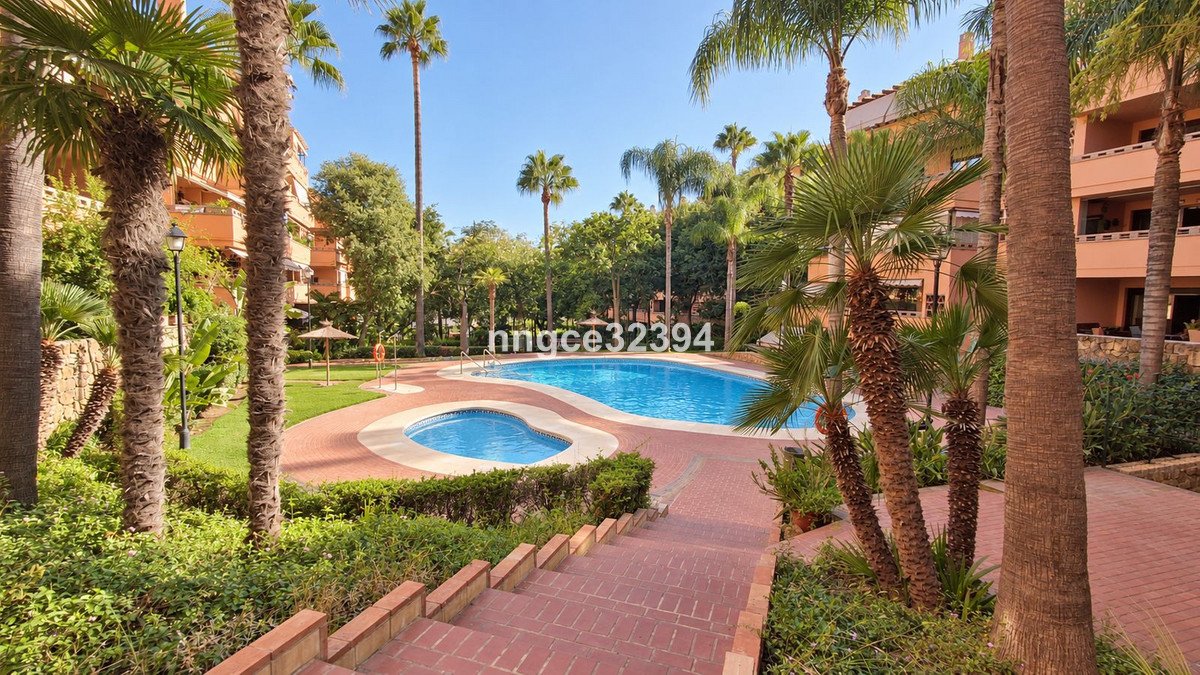 Resort pool area with palm trees, outdoor spaces, and surrounding buildings