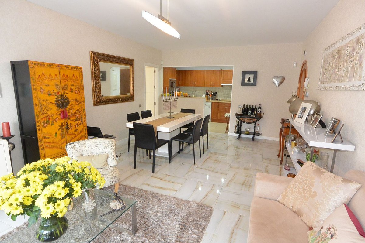 Open plan living, dining, and kitchen area with modern furniture, a large mirror, and decorative items.
