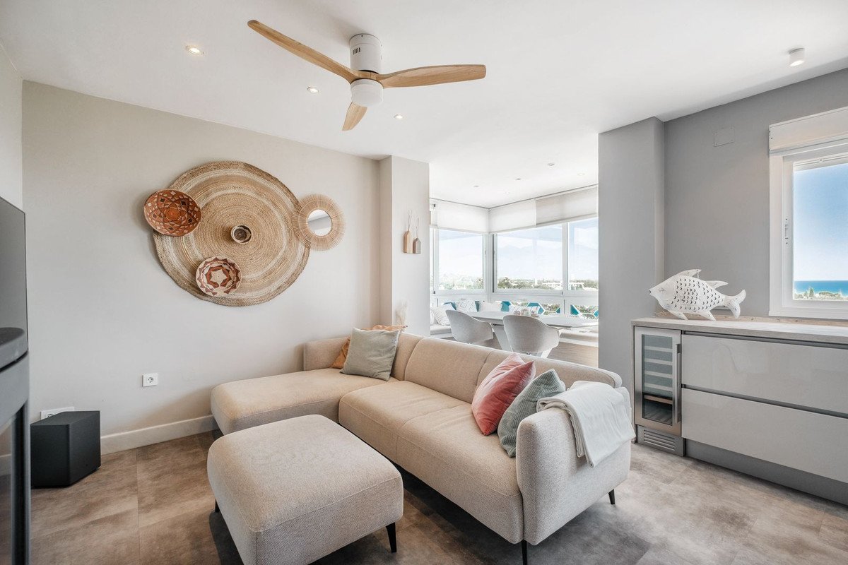 Bright living room with a large sectional sofa, ocean view through windows, and a ceiling fan.