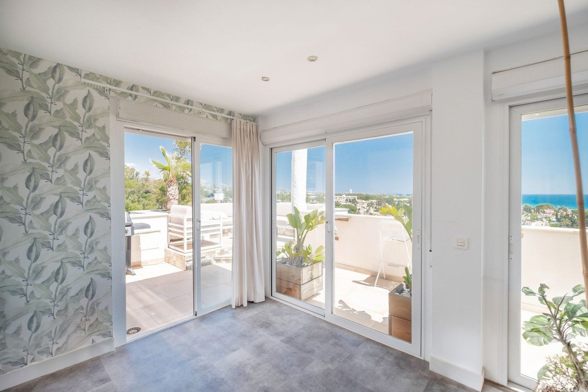 Modern living room with large sliding glass doors opening to a terrace with sea and town views.