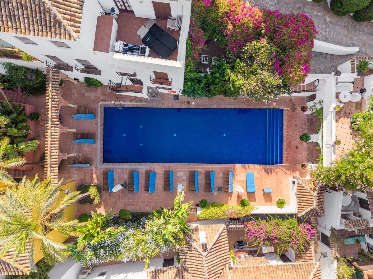 Aerial view of a property featuring a blue swimming pool, sun loungers, lounge areas, and lush vegetation.